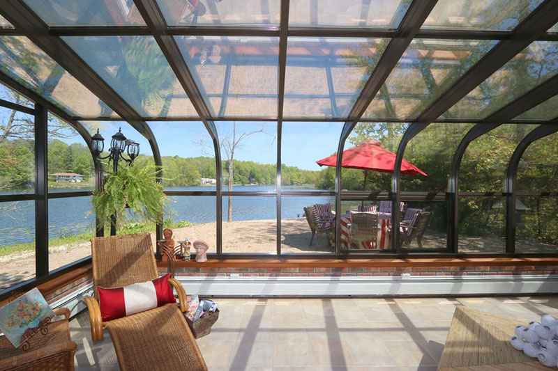 Four Seasons Aluminum Sunroom Constructed Around a Patio with Lounge Chairs in the Left Corner