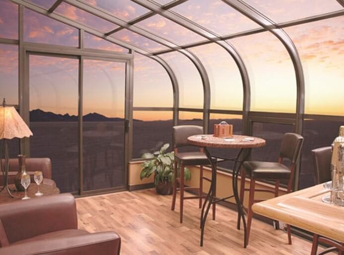 The interior of a curved sunroom showcasing the sunset outside.