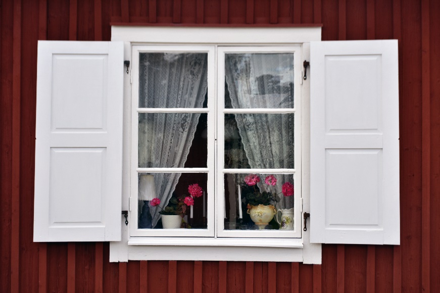 An image of a dark red home with white casement window frames in their open position.